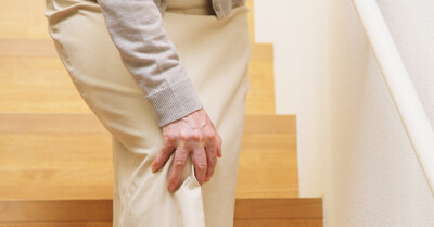 Woman holding sore knee on stairs